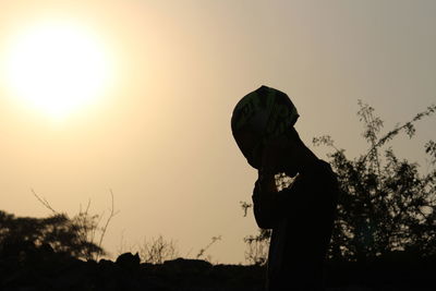 Silhouette woman standing by tree against sky during sunset