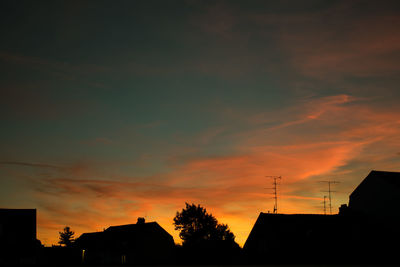 Low angle view of silhouette houses against sky during sunset