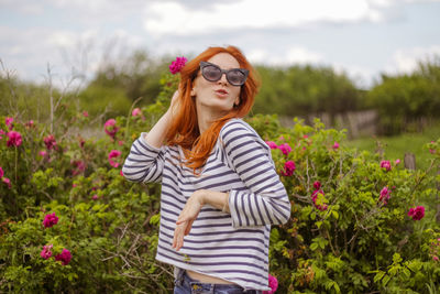 Beautiful young woman near rose bush