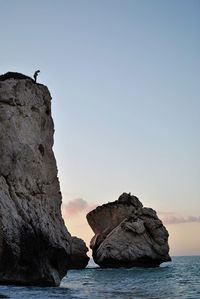 Rock formation in sea against clear sky