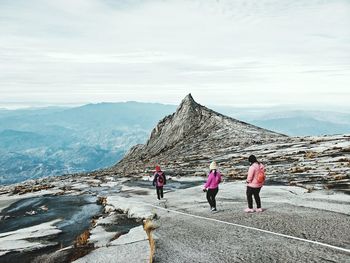 Rear view of people walking on mountain against sky