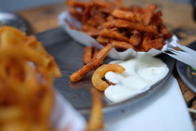 Close-up of onion rings and french fries in plate on table