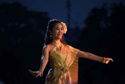 Young woman looking away while standing at night