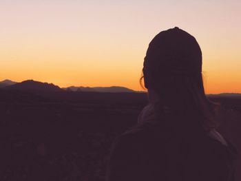 Silhouette woman standing against orange sky