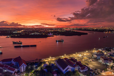 High angle view of illuminated harbor and buildings against sky during sunset