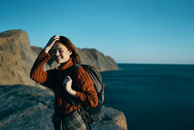 Young woman standing by sea against sky