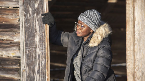 African woman sitting in a doorway in a country barn enjoying the sun in the winter month