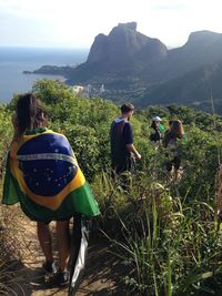 People walking on mountain by sea against sky