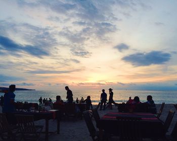 People relaxing on beach at sunset