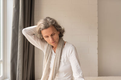 Portrait of woman standing against wall at home