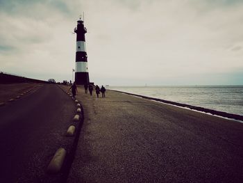 Lighthouse by sea against sky