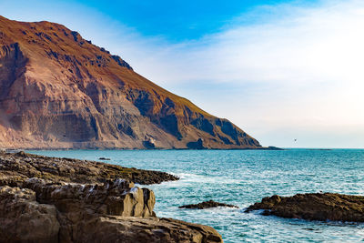 Scenic view of sea by cliff against sky