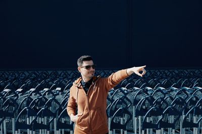 Man pointing while standing against shopping carts