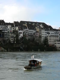 Boat sailing on river in city against sky