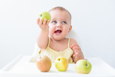 Cute baby girl in baby chair eating apples. baby first solid food