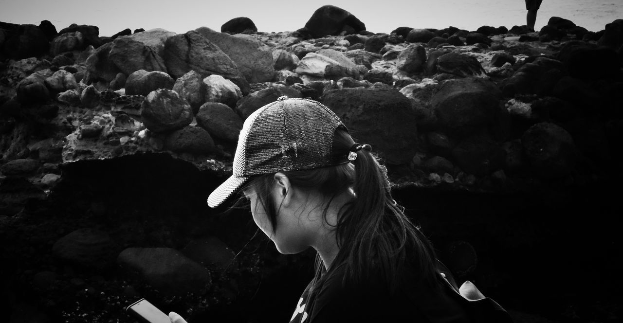 PORTRAIT OF YOUNG WOMAN ON ROCK AGAINST ROCKS