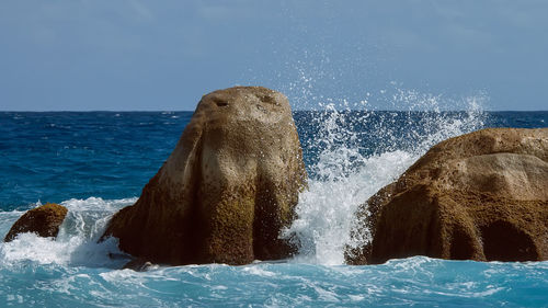 Sea waves splashing on rocks against clear sky
