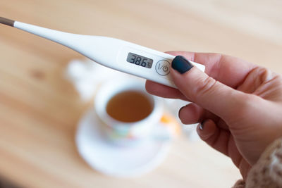 Cropped hand of woman holding thermometer