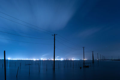 Low angle view of electricity pylon against blue sky