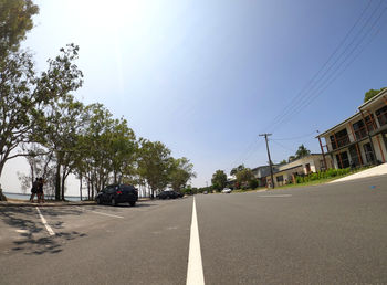 Surface level of road by trees against sky