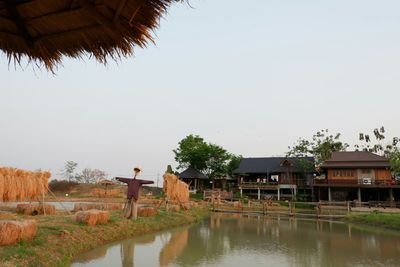 Rear view of man by house against clear sky