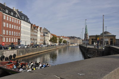 Buildings by river against sky in city