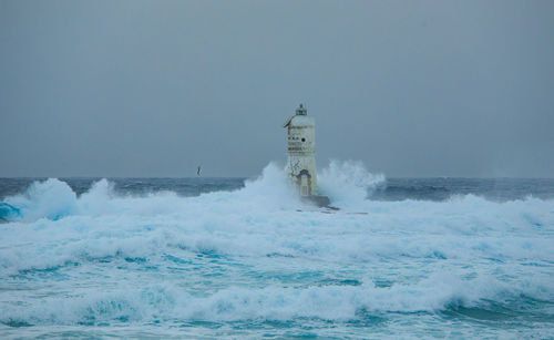 Waves splashing on shore against clear sky