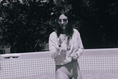 Beautiful woman wearing shirt over bikini in swimming pool during sunny day