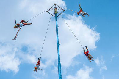 Low angle view of people paragliding against sky