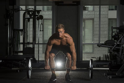 Portrait of young man exercising with barbells at gym