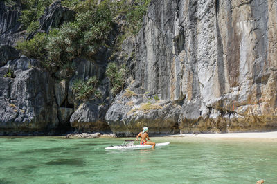 Full length of woman sitting on paddleboard in sea