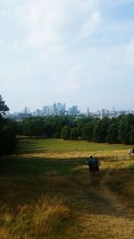 Scenic view of field against sky in city