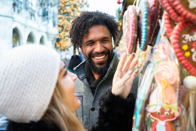 Smiling couple buying gingerbread cookies christmas market