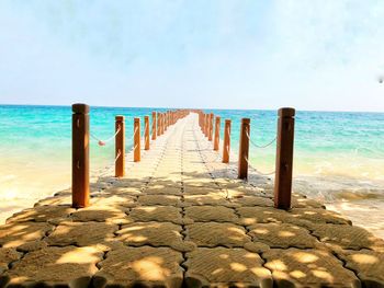 Wooden posts on beach against sky