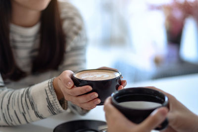 Midsection of woman holding coffee cup at cafe