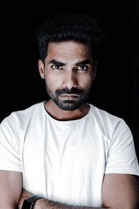 Portrait of young man against black background