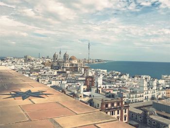 Cityscape by sea against sky