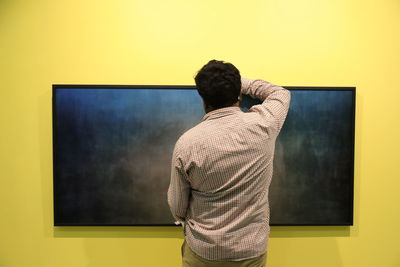 Rear view of man standing against wall