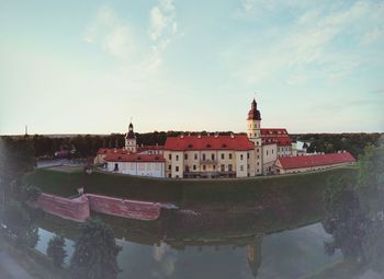 Buildings by river against sky in city