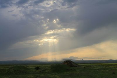 Scenic view of grassy field against cloudy sky