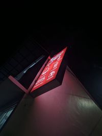 Low angle view of illuminated sign on wall at night