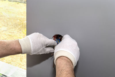 Close-up of man holding hands against wall