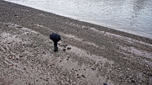 High angle view of man with umbrella standing at beach