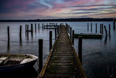 Wooden pier over lake against sky during sunset