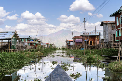 Settlement with shabby traditional residential shacks located on grassy shores near inle lake against blue sky in myanmar on summer day