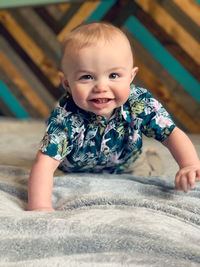 Portrait of cute baby boy sitting on bed at home