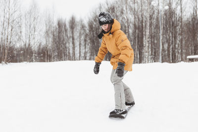 Cute teenage girl rides a snowskate in a winter park, healthy lifestyle