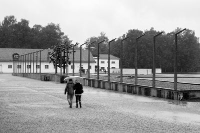 Rear view of people walking on sidewalk against sky