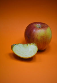 Close-up of apple on table against orange background