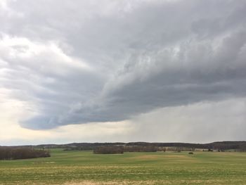 Scenic view of grassy field against cloudy sky